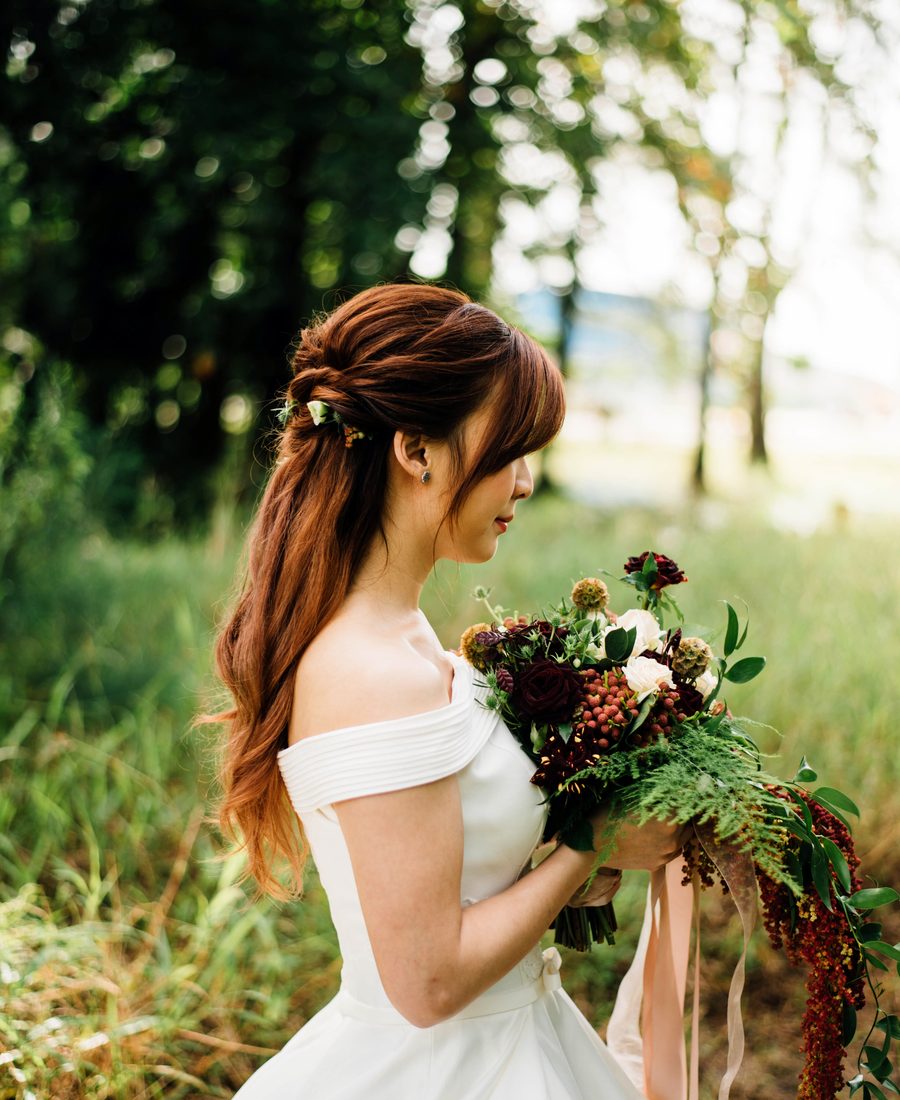 Mariée tenant son bouquet dans un pré